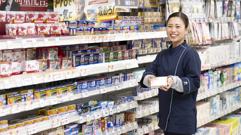 薬の棚の前で従業員が笑顔で、商品をお客さまへご案内している様子。