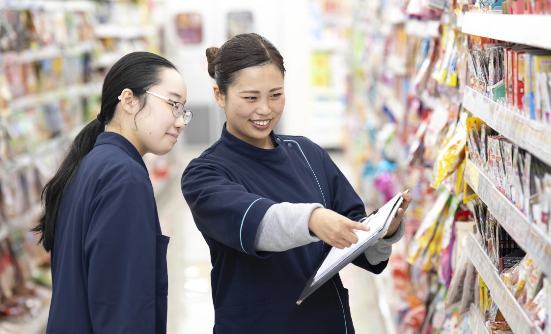 Iさんがバインダーを持ちながら、商品を指さして従業員と会話をしている様子。