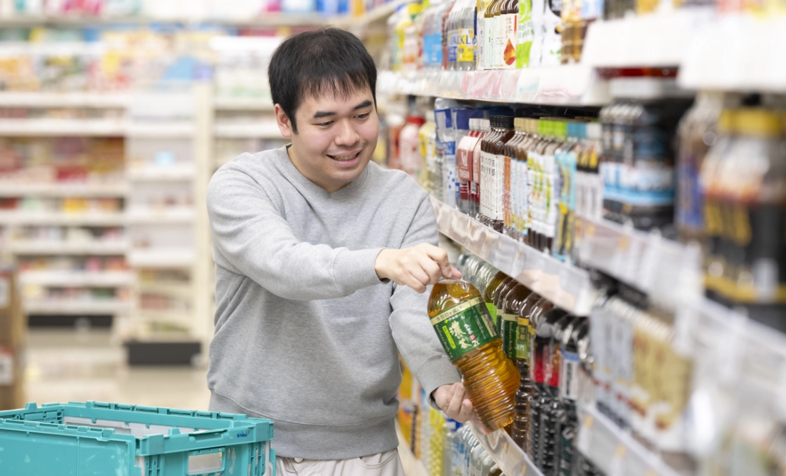Sさんが飲料売場で、カートから新しいペットボトルの飲料を棚へ補充している様子。
